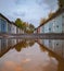 Rows of old garages with colorful gates reflected in puddle