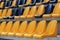 Rows of old plastic black and yellow seats at a stadium