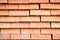 Rows of red bricks ready for transport over the wire fence of the store. Background