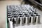 Rows of shiny metal parts with thread created on the factory with a lathe