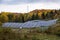 Rows of solar panels at the foot of a wooded hill on a cloudy autumn day