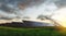 Rows of solar panels at sunset in a field against the backdrop of green grass