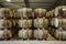 Rows of stacks of traditional full whisky barrels, set down to mature, in a large warehouse