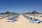 Rows of sun loungers and umbrellas for sunbathing to tourists. Tavira, Portugal, Algarve.