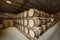 Rows of traditional full whisky barrels, put down to mature, in a large warehouse facility, with acute perspective