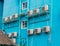 Rows of white conditioners on the turquoise wall, outdoor. Industrial ventilation