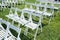 Rows of white folding chairs on lawn