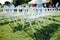 Rows of white folding chairs on lawn