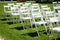 Rows of white folding chairs on lawn before a wedding ceremony in summer