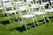 Rows of white folding chairs on lawn before a wedding ceremony in summer