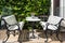 Rows of white wooden benches and tables. Beautiful wooden outdoor furniture stands outside the cafe. Forged black patterned metal