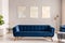 Royal blue settee standing in real photo of light grey living room interior with gold lamps and three simple paintings