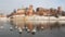 Royal castle on the banks of the Vistula river in Krakow and swans floating in the river in winter