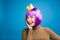 Royal portrait of joyful young woman in luxury dress, gold crown having fun on blue background. Showing tongue