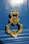 Royal style golden doorknocker on blue wooden door. face