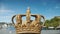 Royal Swedish crown on the Skeppsholmbron bridge over the river with harbor in the background. One of the sights of the