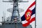 Royal Thai Navy ensign blow on flag pole with Royal Thai Navy Frigate in the background