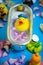 Rubber duck in the bathtub, colorful background with shells, rose petals and other rubber ducks, rubber ducks