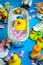 Rubber duck in the bathtub, colorful background with shells, rose petals and other rubber ducks, rubber ducks