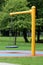 Rubber swing suspended over colorful playground sand with four chains from strong yellow metal pole in local park surrounded with