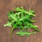 Ruccola leaf on wooden table, pile of fresh green arugula leaves collection top view