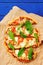 Rucola pizza on wrinkled craft paper with blue background