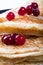 Ruddy pancakes on a black plate with red berries of a cranberry