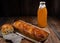 Ruddy pie with orange filling, bottle of pumpkin juice, wooden table, rustic style