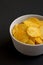 Ruffled Cheese Potato Chips in a Bowl on a black surface, side view