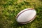 Rugby sports field with green grass for the game of rugby. Focus on ball, sports base at background.