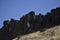 Rugged black Rock towering atop a high desert canyon wall