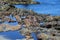 Rugged boulders along the shore of a blue ocean