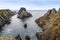 Rugged landscape at Malin Head, County Donegal, Ireland. Beach with cliffs, green rocky land with sheep on foggy cloudy