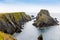 Rugged landscape at Malin Head, County Donegal, Ireland. Rough beach with cliffs, green rocky land with sheep on foggy