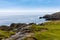 Rugged landscape at Malin Head, County Donegal, Ireland. Rough beach with cliffs, green rocky land with sheep on foggy