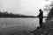 Rugged outdoors fisherman standing on bank of fast flowing river