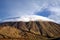 Rugged volcano cone Pico del Teide with cuddly soft white deep hanging  cumulus cloud cap on canary island Tenerife