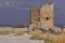 Ruin of old ancient stone destroyed tower Genoese fortress in Feodosia made of white sand colored bricks among dry yellow grass