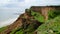 Ruined clay slope by the sea. Cracked clay cliff on the coast.