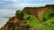 Ruined clay slope by the sea. Cracked clay cliff on the coast.