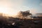 ruined industrial building in desolate and barren landscape, with smoke rising from its ruins