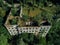 Ruined overgrown school in ghost mining town Akarmara, consequences of war in Abkhazia, aerial view from drone