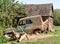 Ruined rusty car standing on green grass near rural buildings