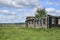 a ruined wooden farmhouse under a blue sky.