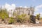 Ruins of an abandoned house covered in shrubs. Concrete grey bro