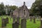 Ruins of a ancient church at Blairdaff Burial Grounds, Scotland with grey sky and tombstones