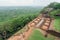 Ruins of ancient city palace on Sigiriya rock and some tourists walking around archeological area