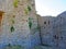 The ruins of an ancient fortress. old thick stone walls of a European fortress overgrown with greenery in the mountains. Doors and