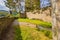 Ruins of the castle of Esch-sur-Sure, green grass with trails between a old fence and stone walls