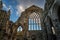 The ruins of Holyrood Abbey still stand tall silhouetted by blue sky and fluffy clouds behind the Queen`s Gallery Palace